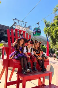 Tres niños sonrientes disfrazados de bruja, pirata y gato negro
